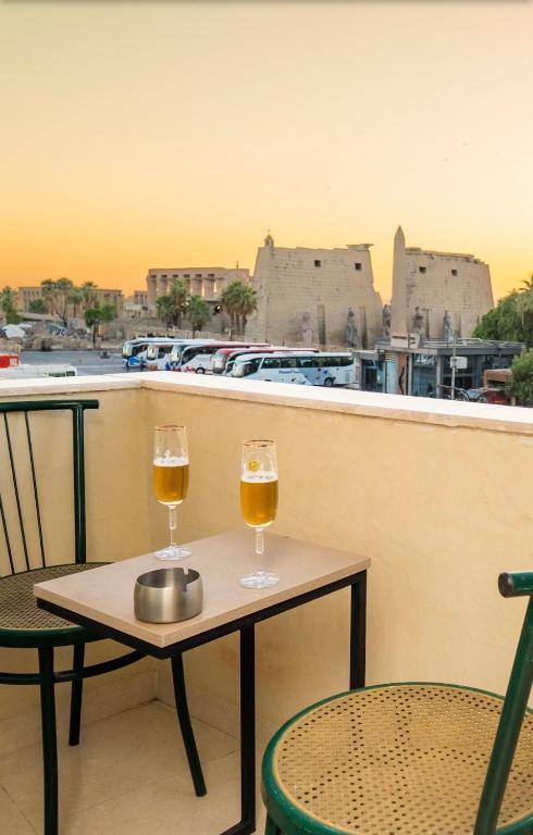 two glasses of beer on a table on a balcony at Temple & Nile view in Luxor