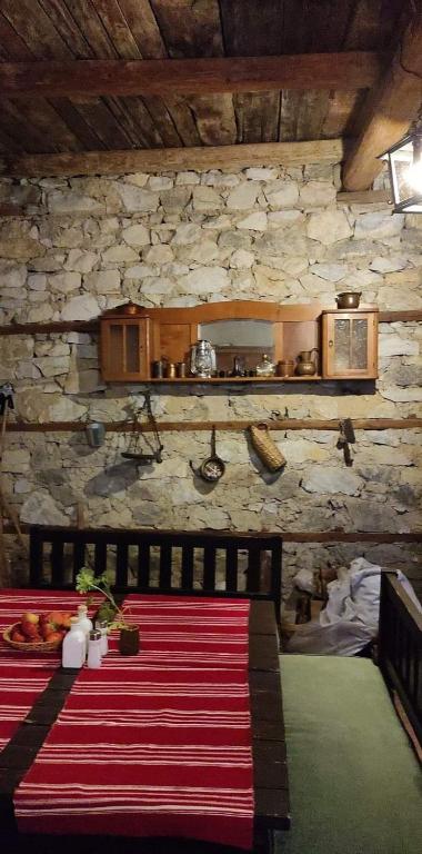 a dining room with a table and a stone wall at Кулинарна къща за гости СОФРИЦА in Hvoyna