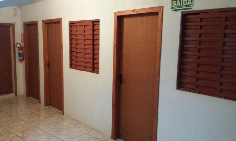 Un pasillo con tres puertas y dos ventanas en una habitación. en Hotel Pousada Do Viajante, en Erechim