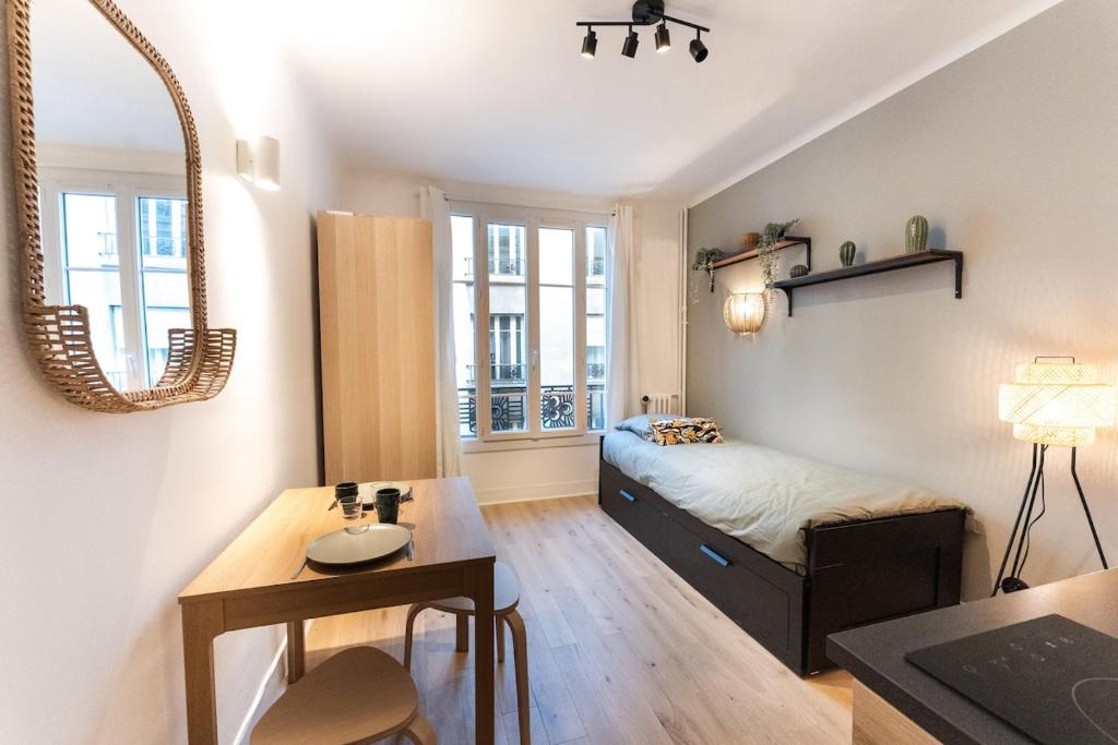 une chambre avec un lit, une table et un miroir dans l'établissement Beautiful studio near Eiffel Tower and Beaugrenelle, à Paris
