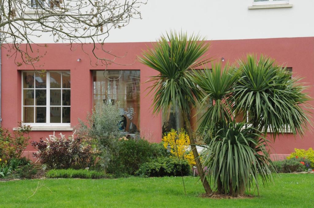 un bâtiment rouge avec des palmiers dans une cour dans l'établissement Spacious & bright property on D-Day Beaches, à Ver-sur-Mer