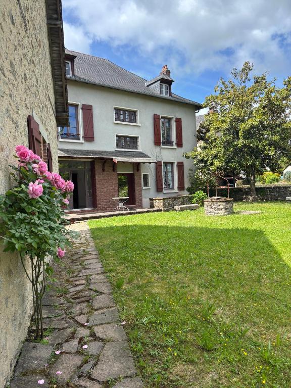 une maison avec des fleurs roses sur son côté dans l'établissement Maison Mère, à Arnac-Pompadour
