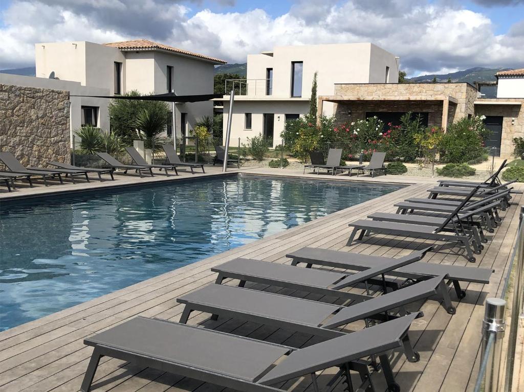 une piscine avec des chaises longues à côté d'un bâtiment dans l'établissement Villa ASTRAGALE T3, à Lecci