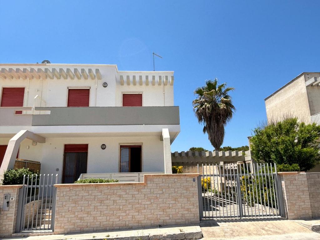 una casa blanca con una valla y una palmera en Casa Marpe by JDvacanze, en San Pietro in Bevagna