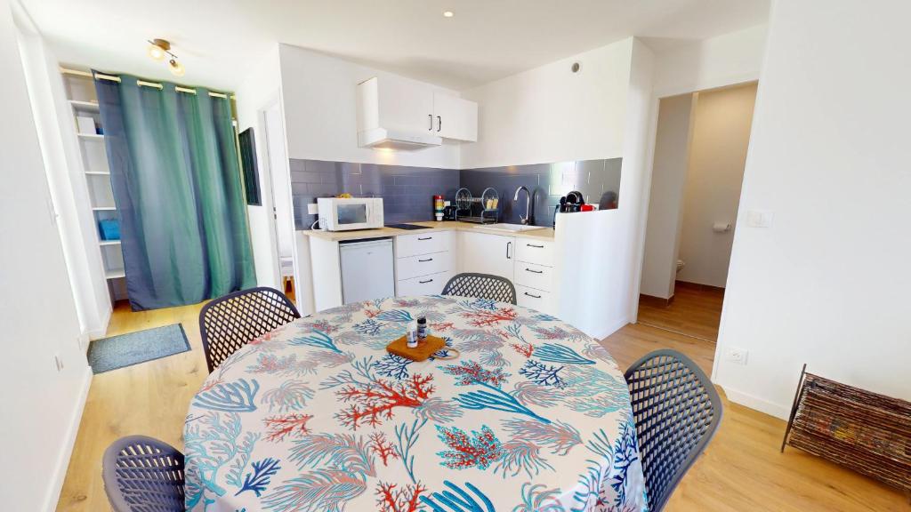 une table de salle à manger avec des chaises et une cuisine dans l'établissement Le Nid de la Mouette, à Saint-Hilaire-de-Riez
