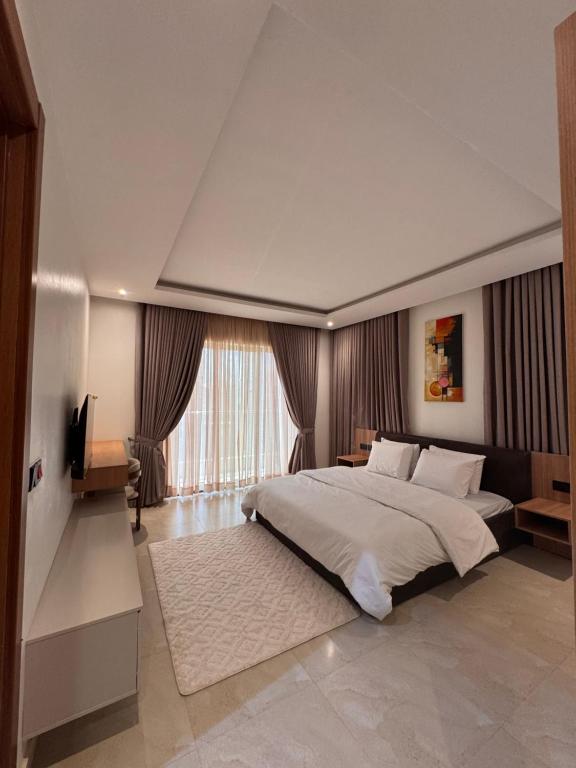 a bedroom with a large bed and a large window at D-GioGiNi Apartments in Gwarinpa