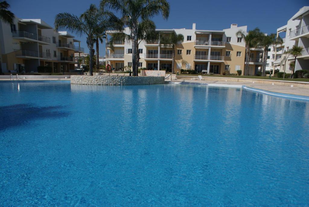 a large blue swimming pool with buildings in the background at Vila da Praia 7D Alvor in Alvor