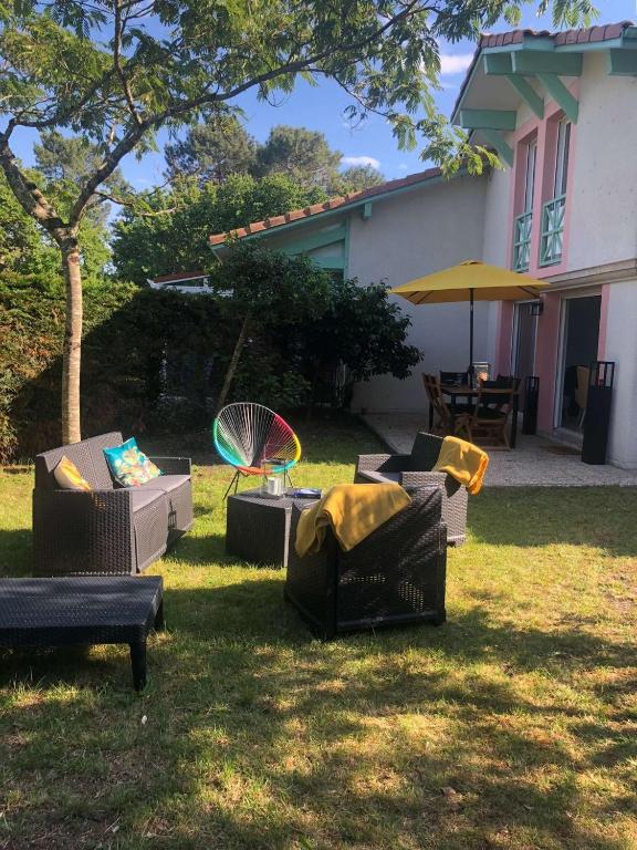 un groupe de chaises et de tables dans une cour dans l'établissement Maison mitoyenne avec beau jardin proche lac, à Biscarrosse