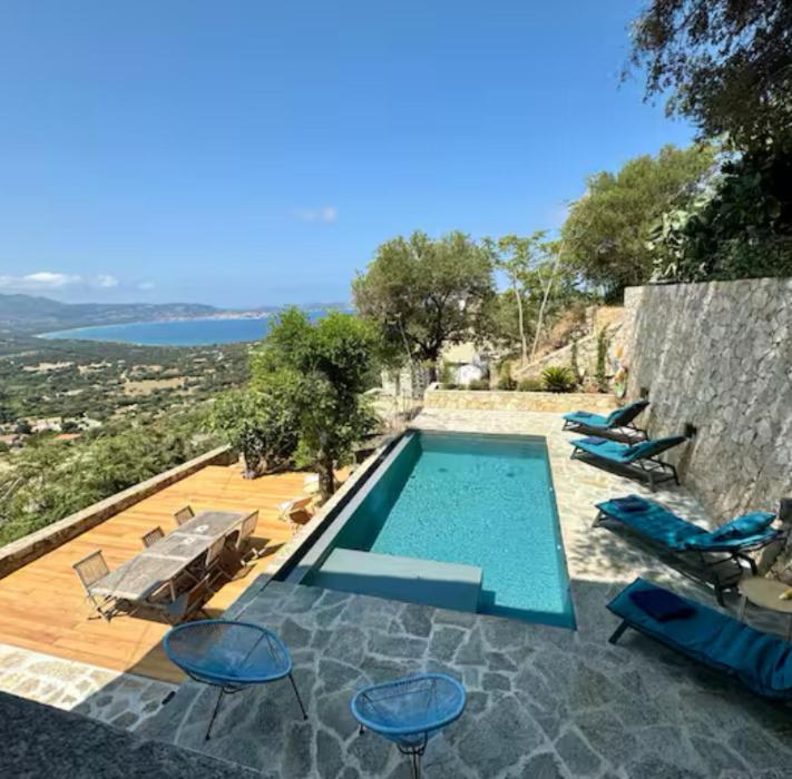 - une piscine avec des chaises bleues dans l'établissement Maison de village atypique A Cappella, à Lumio