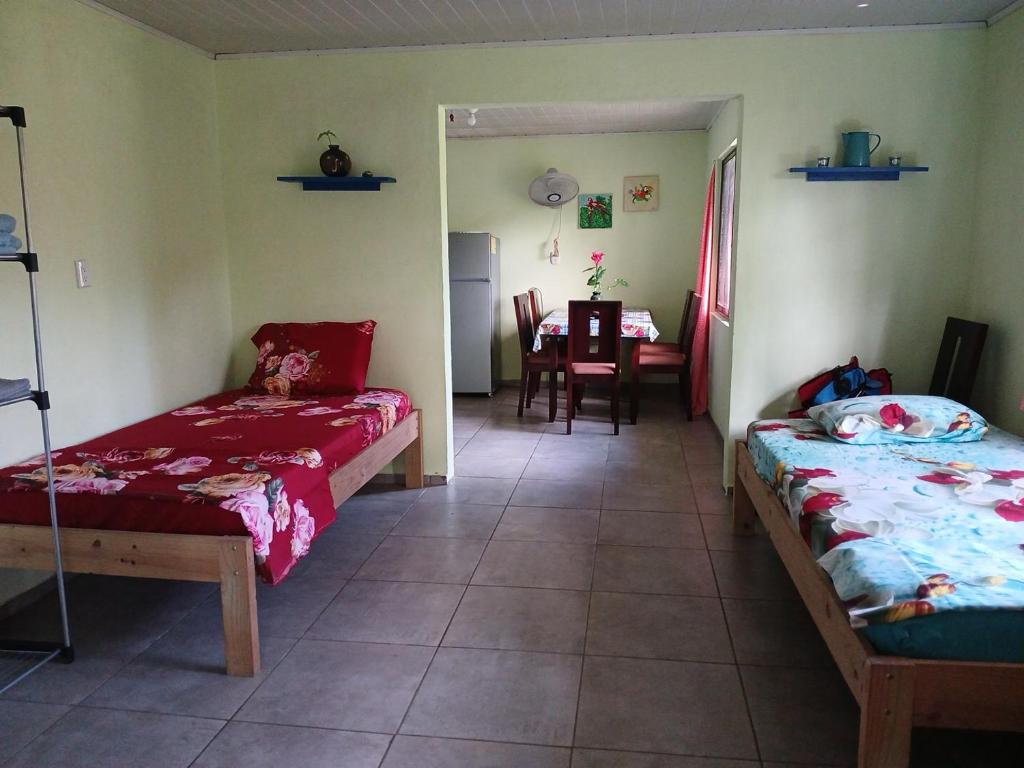 a room with two beds and a dining room with a table at Casa Shakira in Puerto Jiménez