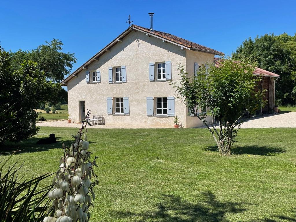 une grande maison en pierre avec une cour herbeuse en face de celle-ci dans l'établissement La Petite Maison, à Lagardère