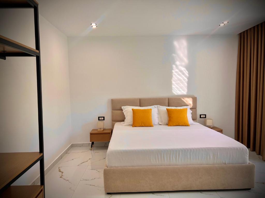 a bedroom with a large bed with two yellow pillows at Dine Hotel in Ksamil