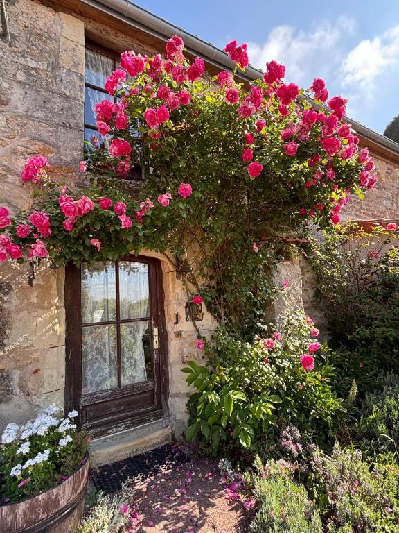 une porte fleurie devant un bâtiment dans l'établissement Domaine les roses du vieux chai, à Doué-la-Fontaine