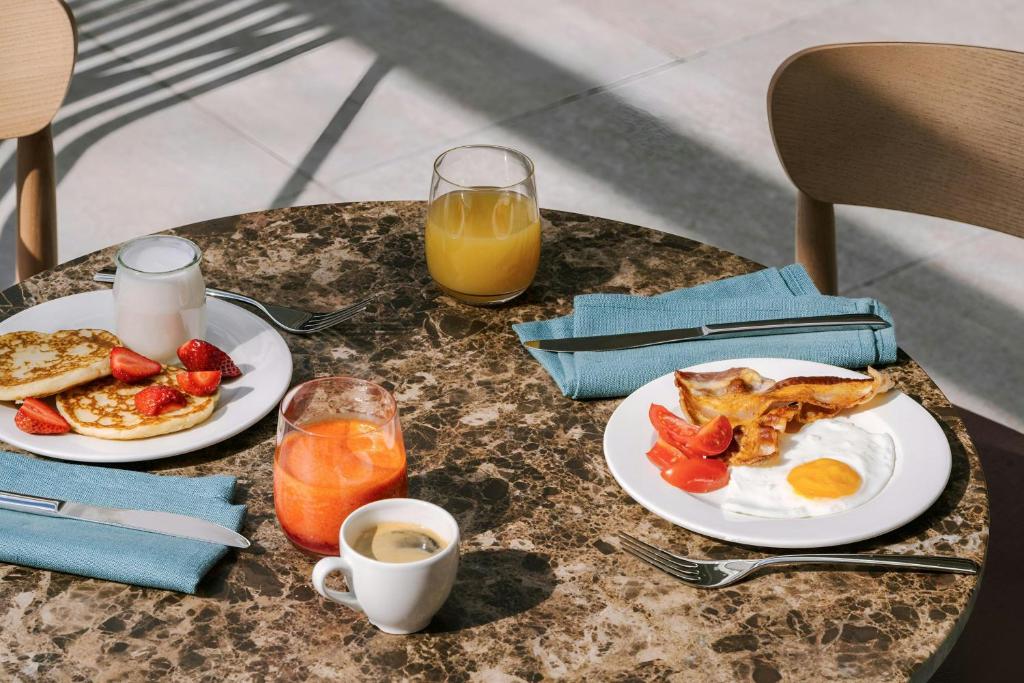 a table with two plates of breakfast food and orange juice at Testaccio Hotel Monte dei Cocci, Sonder by Marriott Bonvoy in Rome