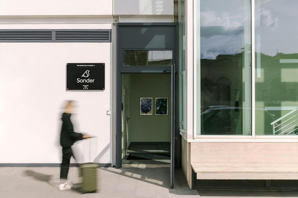 a woman walking outside of a building with a sign on it at Testaccio Hotel Monte dei Cocci, Sonder by Marriott Bonvoy in Rome