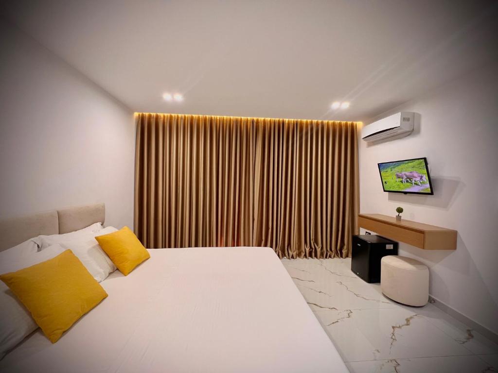 a bedroom with a bed with yellow pillows and a window at Dine Hotel in Ksamil