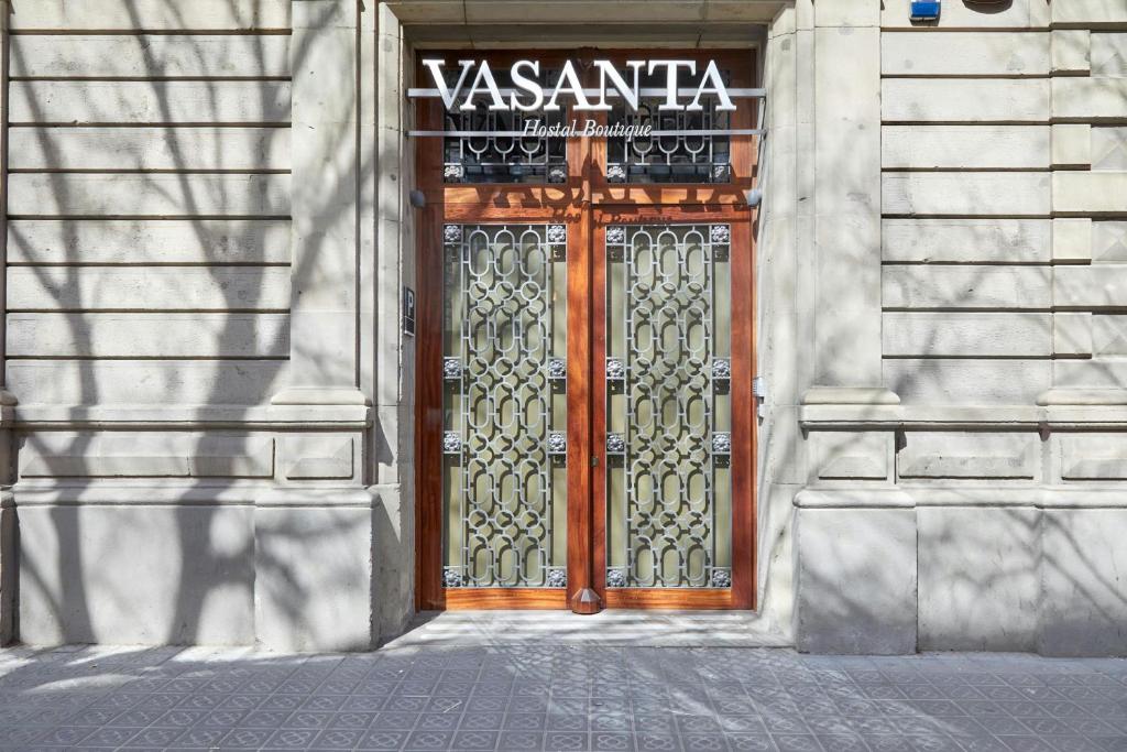 a wooden door on a building with a sign on it at Hotel Vasanta in Barcelona