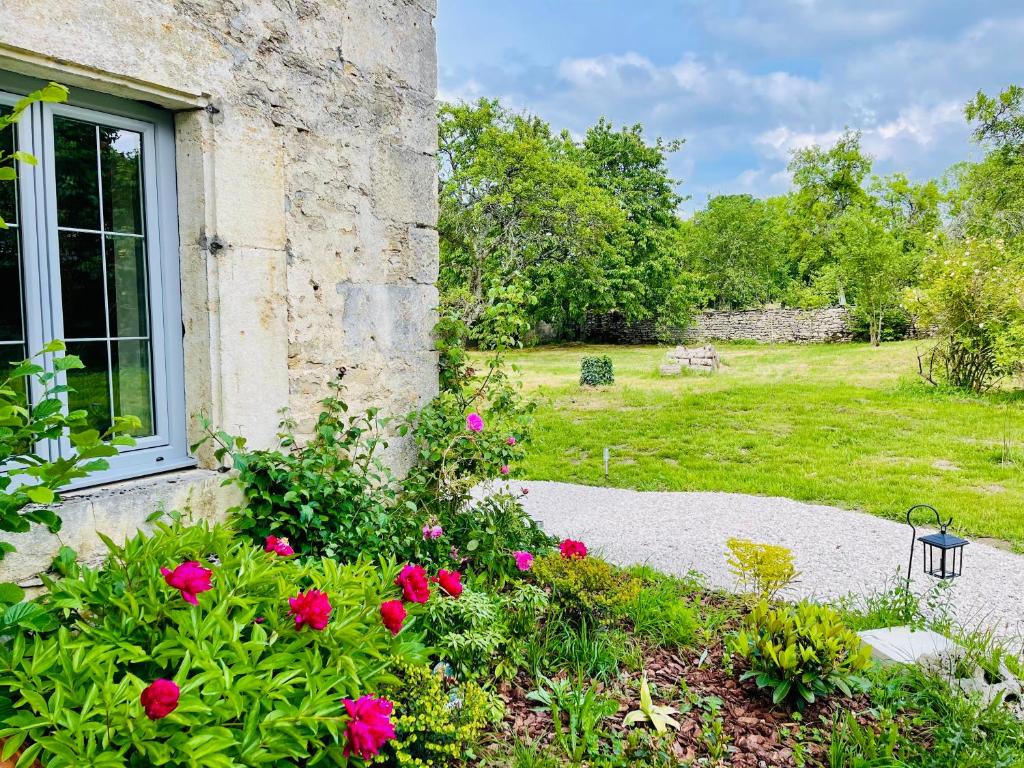 un jardin avec des fleurs roses à côté d'un bâtiment dans l'établissement Le Prieuré de Saint Broing, 