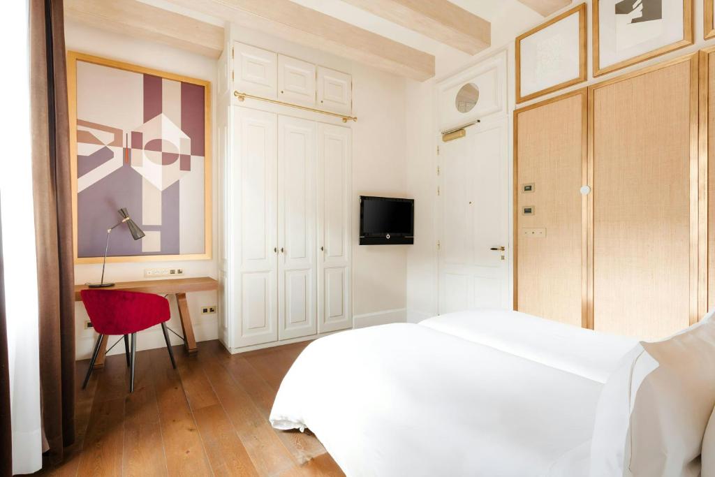 a bedroom with a white bed and a red chair at DO Plaça Reial Hotel Gothic Quarter, Sonder by Marriott Bonvoy in Barcelona