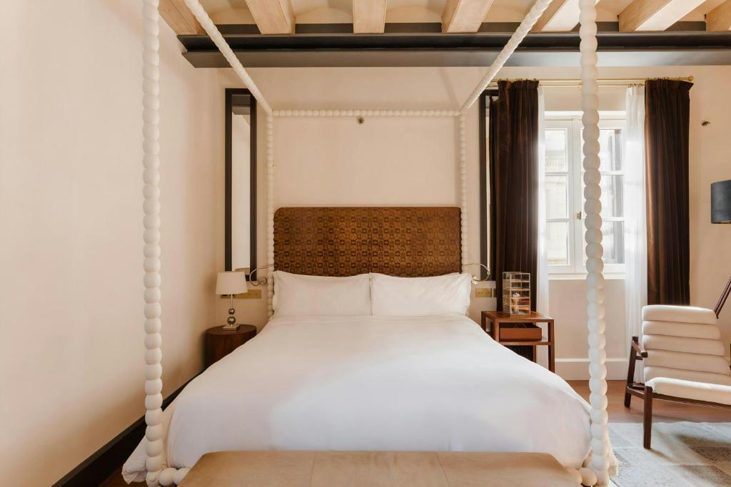 a bedroom with a white canopy bed with a chair at DO Plaça Reial Hotel Gothic Quarter, Sonder by Marriott Bonvoy in Barcelona