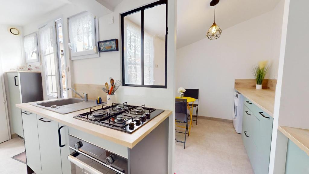 Il comprend une cuisine équipée d'une cuisinière. four supérieur à côté d'un évier dans l'établissement Maison de vacances proche du Port, à Saint-Gilles-Croix-de-Vie