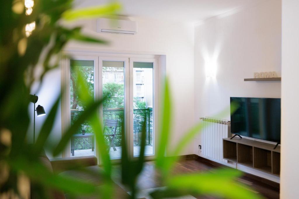 a living room with a television and a balcony at Ostia Bella Apartment in Lido di Ostia