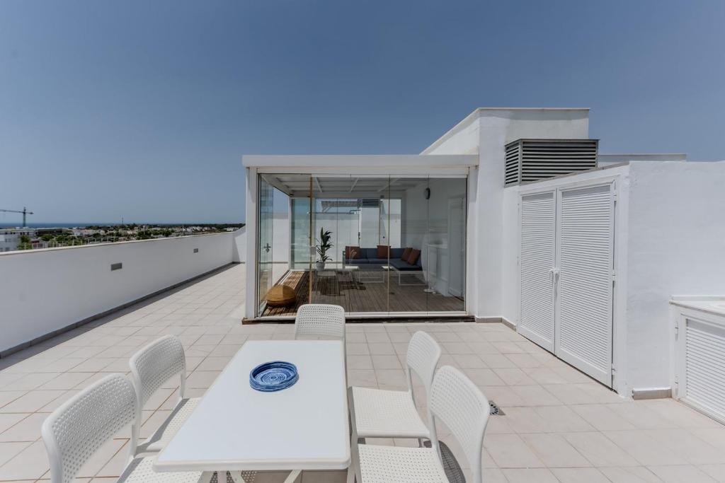 een patio met een witte tafel en stoelen op een dak bij Balcones Olehousing in Conil de la Frontera