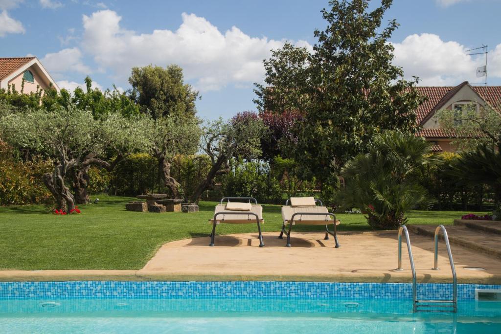 a swimming pool with two benches next to a yard at Casa Del Jazz in Piazza Armerina