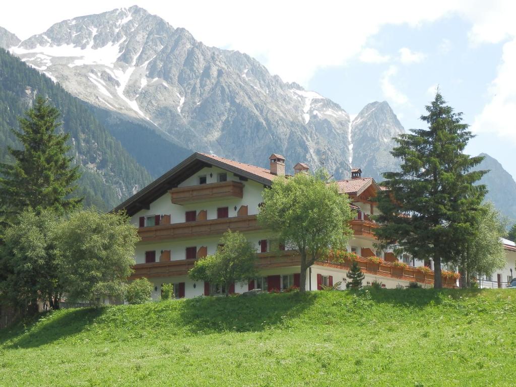 a building on a hill with mountains in the background at Kühlerhof in Anterselva di Mezzo