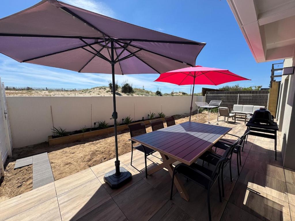 a patio with a table and two umbrellas at Bord de mer exceptionnel label 4 étoiles "Clevacances" in Marseillan