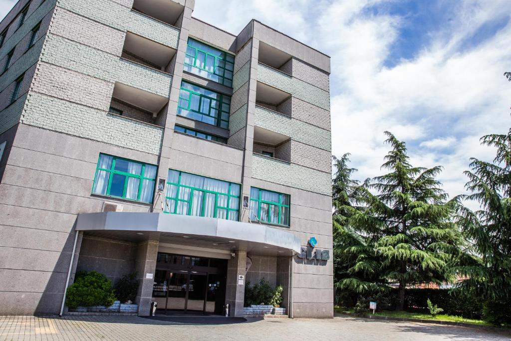 un edificio alto con ventanas azules delante de él en Hotel Glis, en San Mauro Torinese