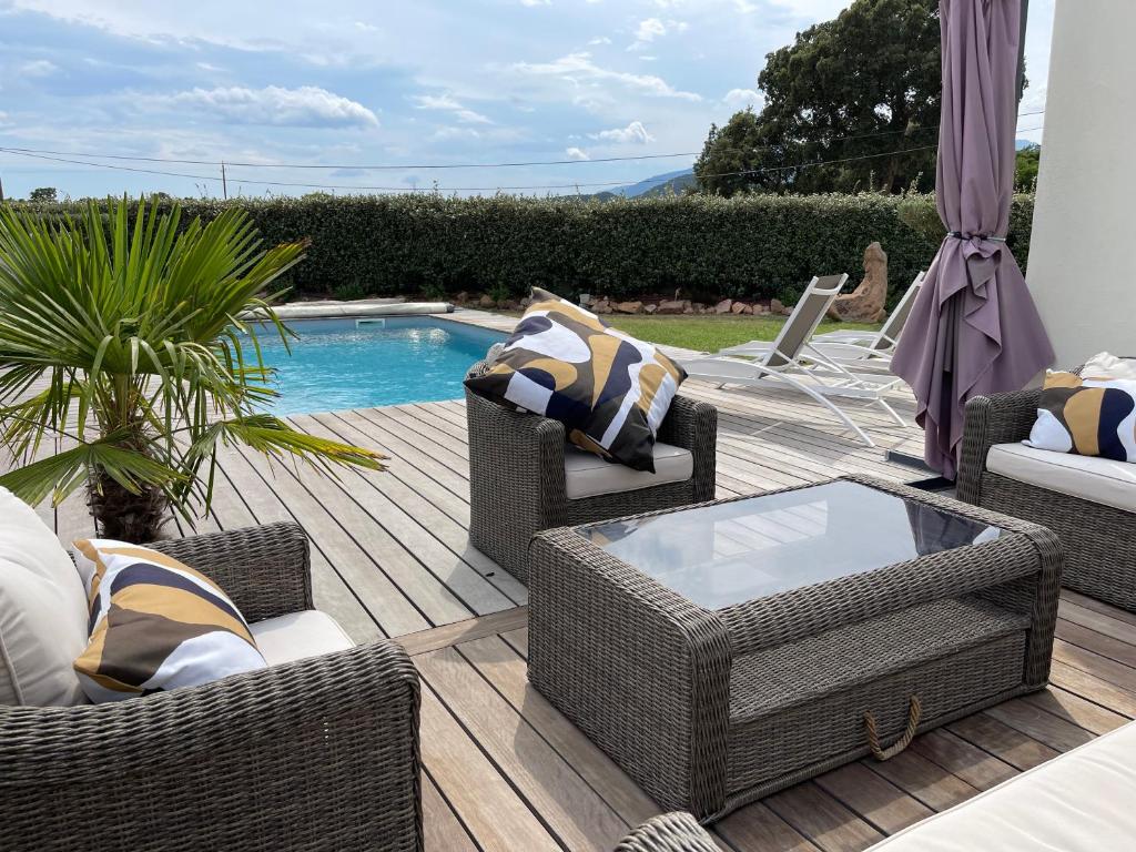 une terrasse avec des chaises en osier et une piscine dans l'établissement Villa Porto Vecchio, à Porto-Vecchio