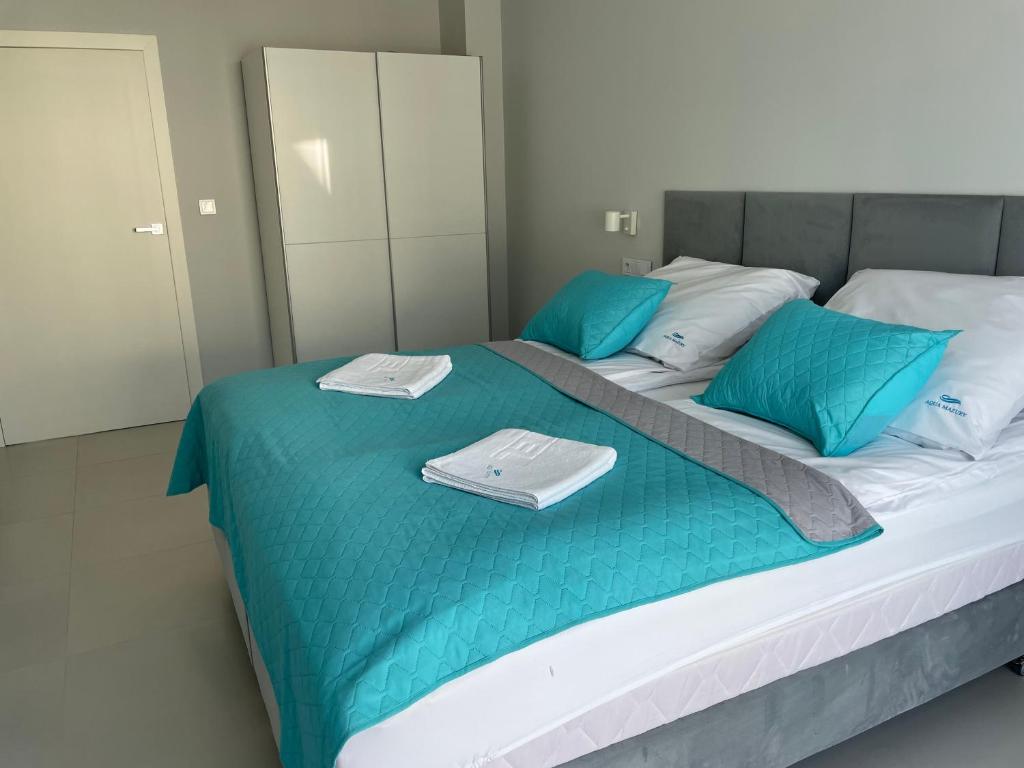 ein Bett mit blauen Kissen und Handtüchern darauf in der Unterkunft Apartament Aqua Mazury z jacuzzi in Lyck