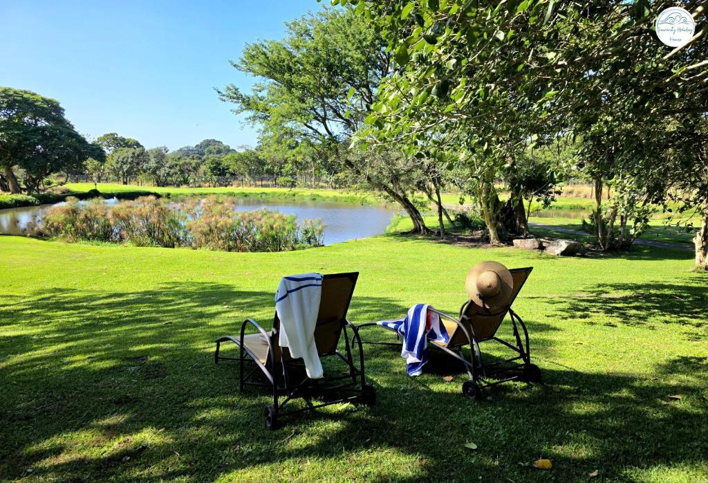 two chairs sitting in the grass next to a lake at Villa G5 - Selborne Golf Estate in Pennington