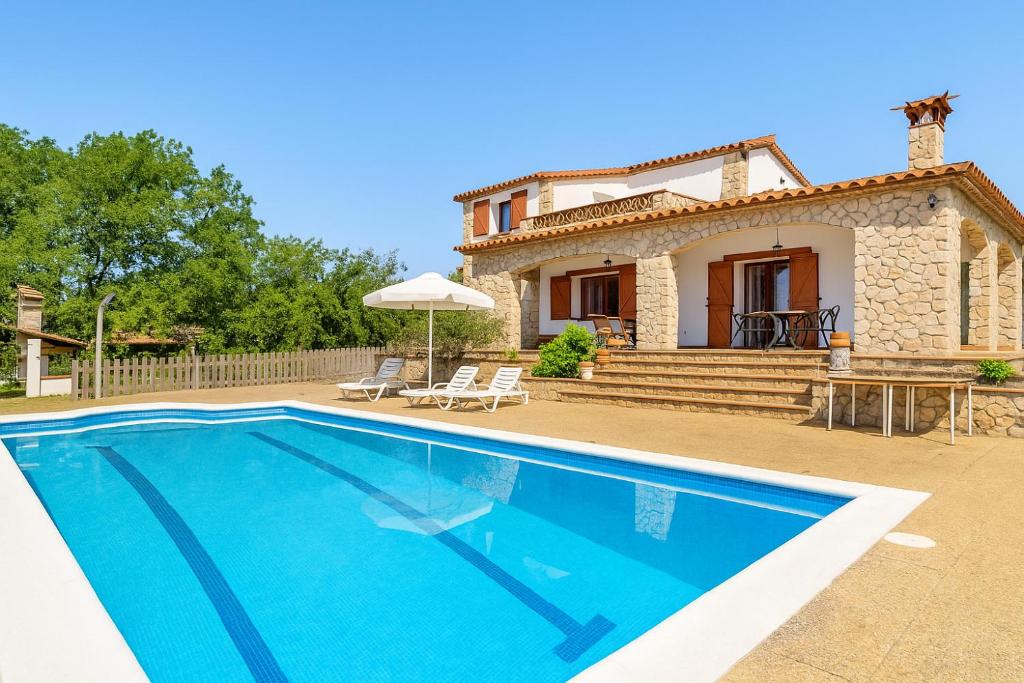 a villa with a swimming pool in front of a house at Ca la Goyi in Caldes de Malavella