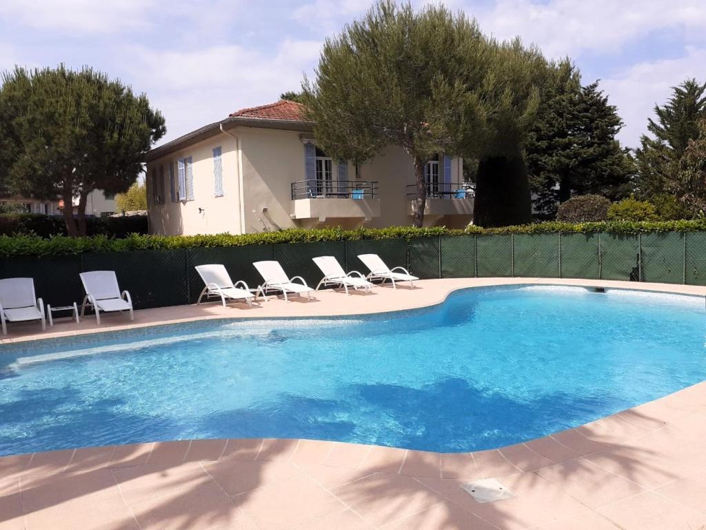 a swimming pool with chairs and a house at Hôtel Beau Site - Cap d'Antibes in Antibes