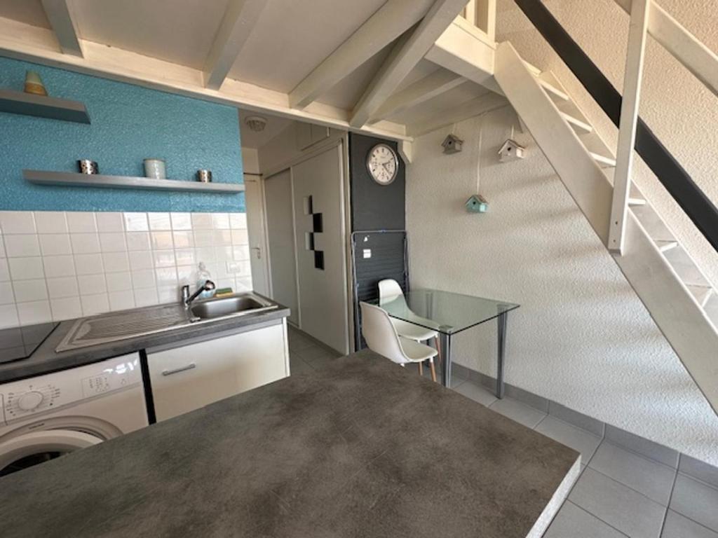 une cuisine avec un évier et une table ainsi qu'un escalier dans l'établissement Studio mezzanine climatisé 4 pers à Le Barcarès - FR-1-799-56, au Barcarès