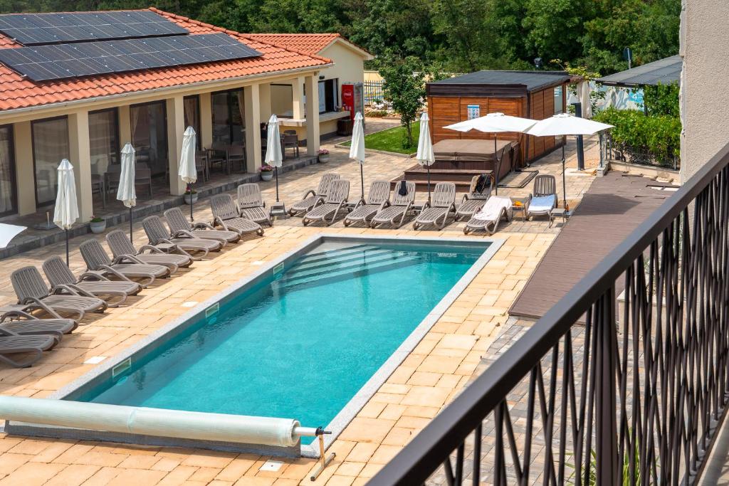 a swimming pool on a balcony with chairs and umbrellas at VSG Resort - Relaxing Apartments, 200m from the Sea, with Pool, Sauna & Jacuzzi in Klimno