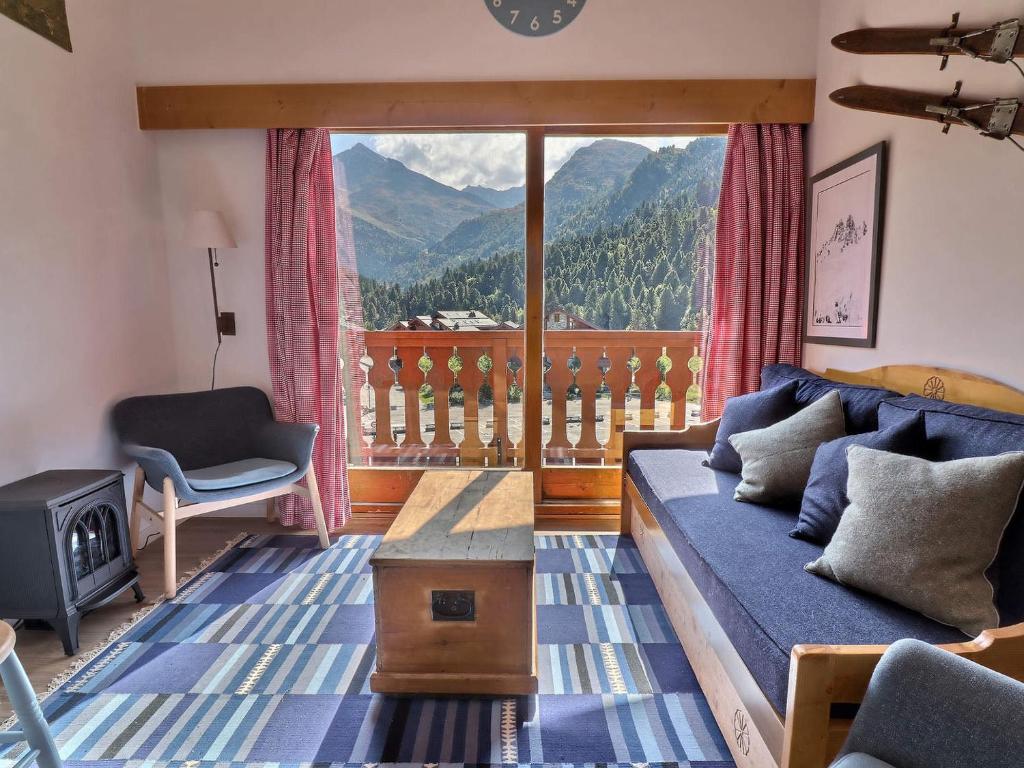 un salon avec un canapé et une grande fenêtre dans l'établissement Charmant Duplex Skis aux Pieds, Proche Commerces, Méribel - FR-1-182-109, à Méribel