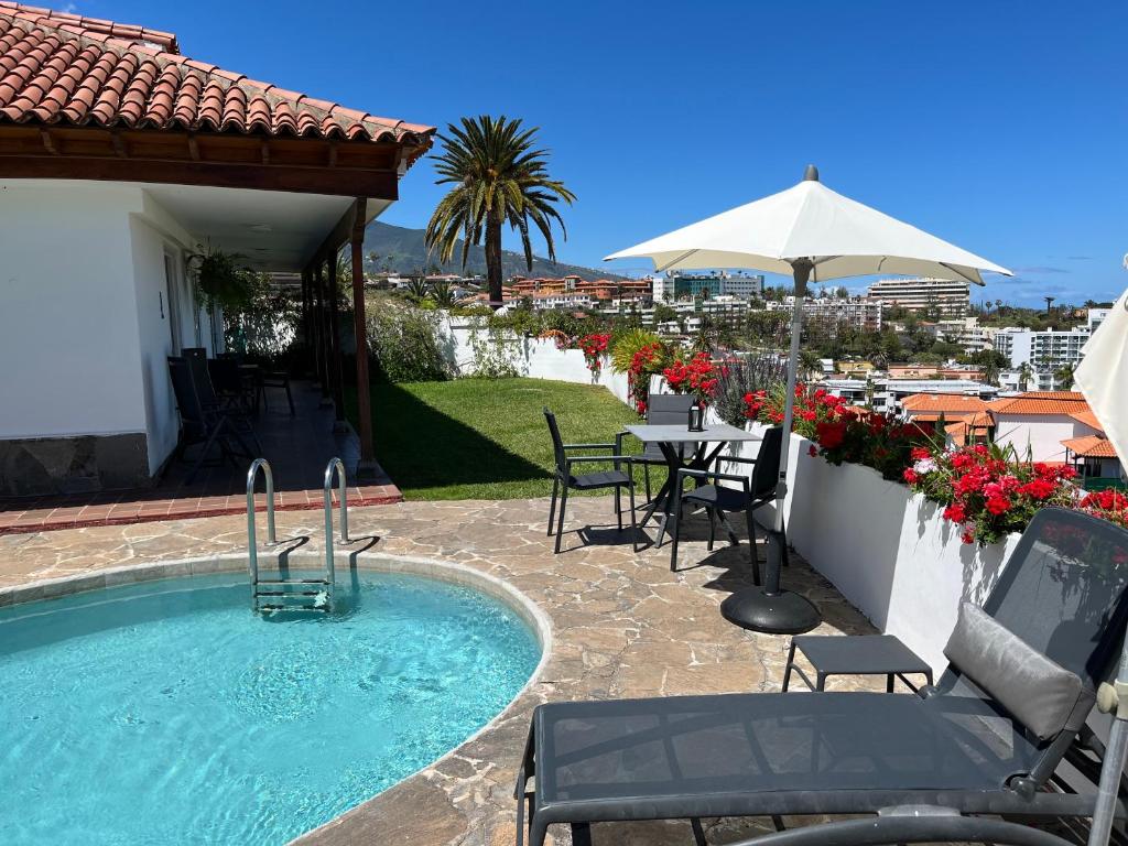 basen z krzesłami, stołem i parasolem w obiekcie Casa Janni with heated private pool w Puerto de la Cruz