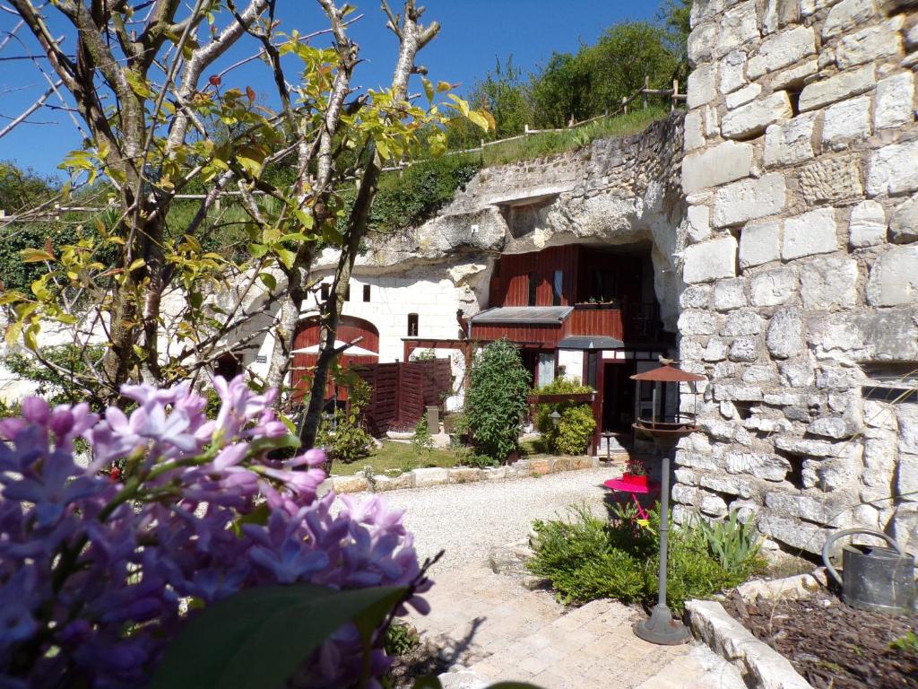 un jardin avec des fleurs violettes devant un bâtiment en pierre dans l'établissement Les Troglos de Beaulieu, à Loches