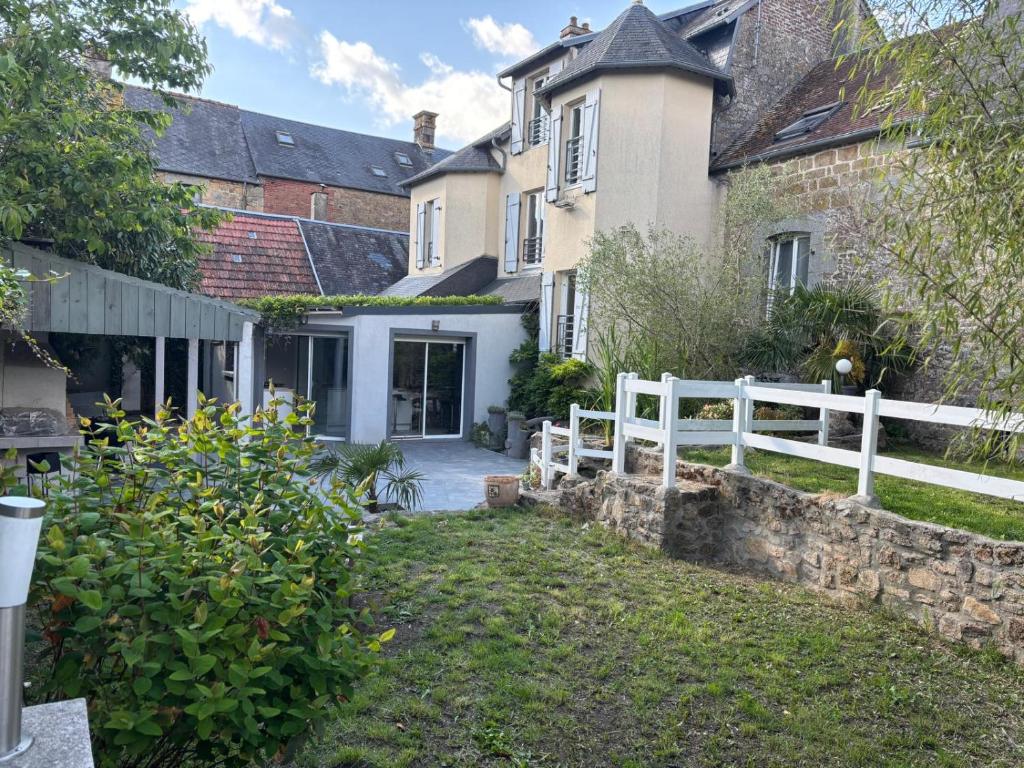 een wit hek voor een huis bij Maison de ville avec jardin clos in Carrouges