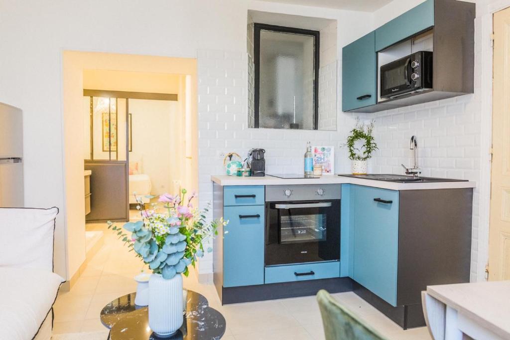 una cucina con armadi blu e un vaso di fiori su un tavolo di Le Herriot Hyper Centre 5min de la Gare à pied a Brive-la-Gaillarde