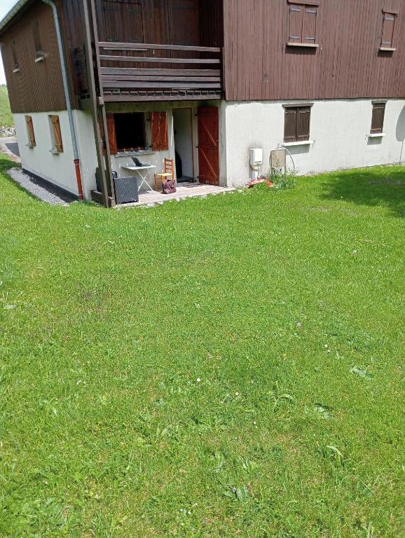 une grange avec une pelouse devant elle dans l'établissement Appartement BOIS D'AMONT, à Bois-dʼAmont