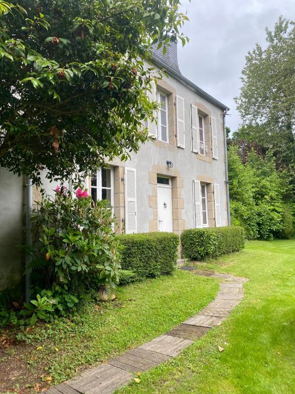 une maison blanche avec une porte et quelques buissons dans l'établissement Maison entre campagne et mer, à Lanvellec