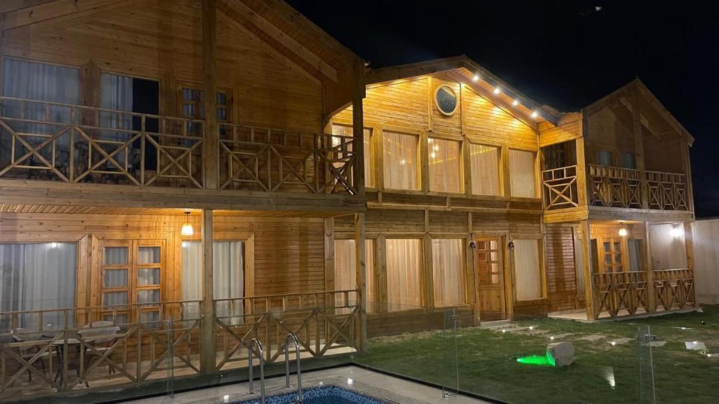 a large wooden building with a pool in front of it at أكواخ القرية -VILLAGE HUTs in Taif