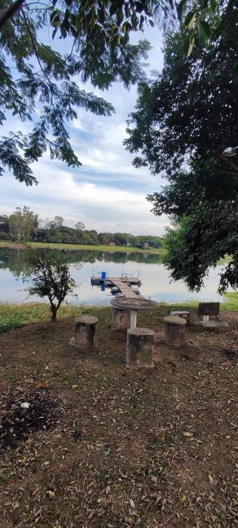 a picnic table next to a lake with a boat at Rancho na Represa in Carlópolis