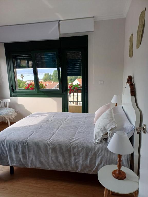 a white bedroom with a bed and two windows at A casa da Piruleta in Bueu