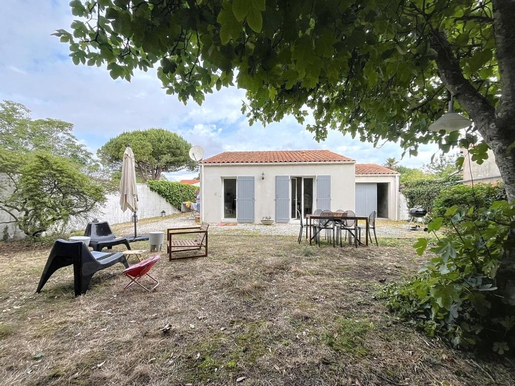 une maison avec une cour dotée de chaises et d'un parasol dans l'établissement Maison bourg de Saint Pierre Oleron, à Saint-Pierre-dʼOléron