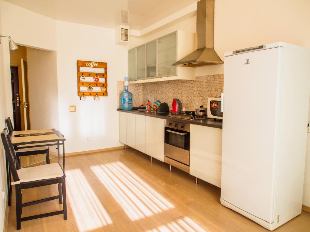 a kitchen with a refrigerator and a table in it at Vtoroy Dom Apartments - Yekaterinburg in Yekaterinburg